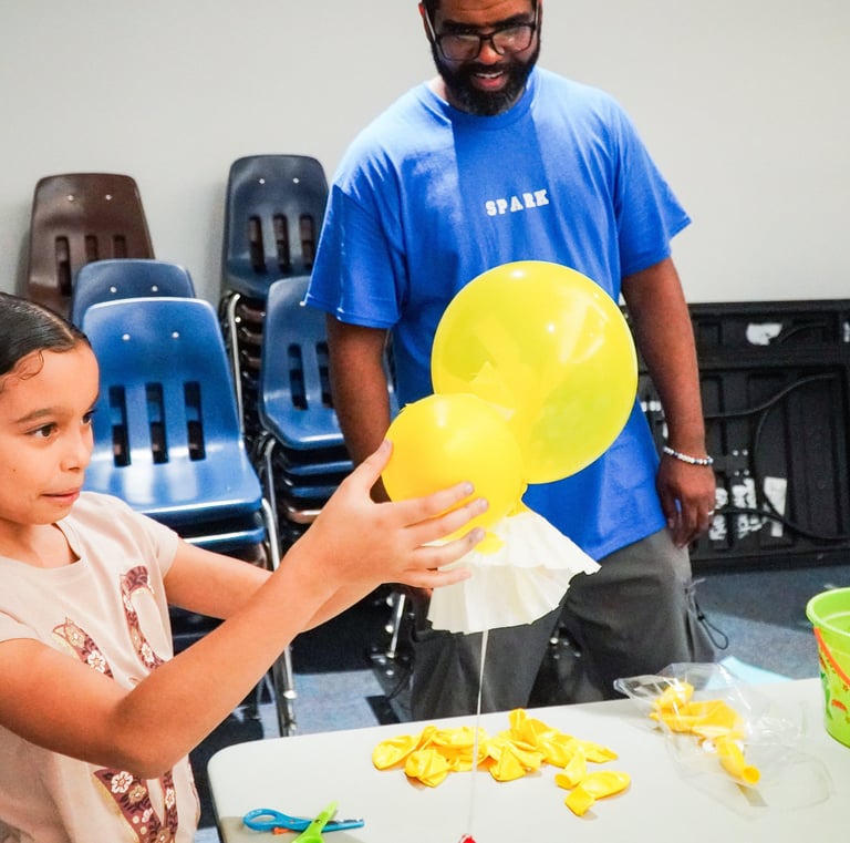 a young girl holding a yellow balloon in a classroom as part of her space capsule landing system