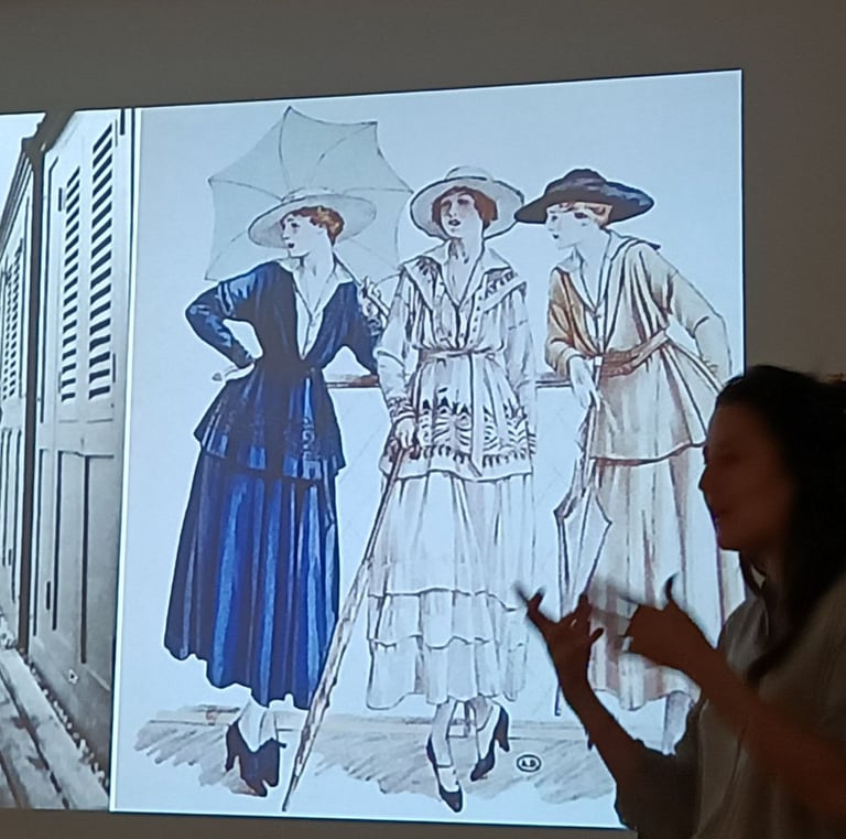 Une conférencière présente une illustration de la mode féminine et des robes d’époque vintage.