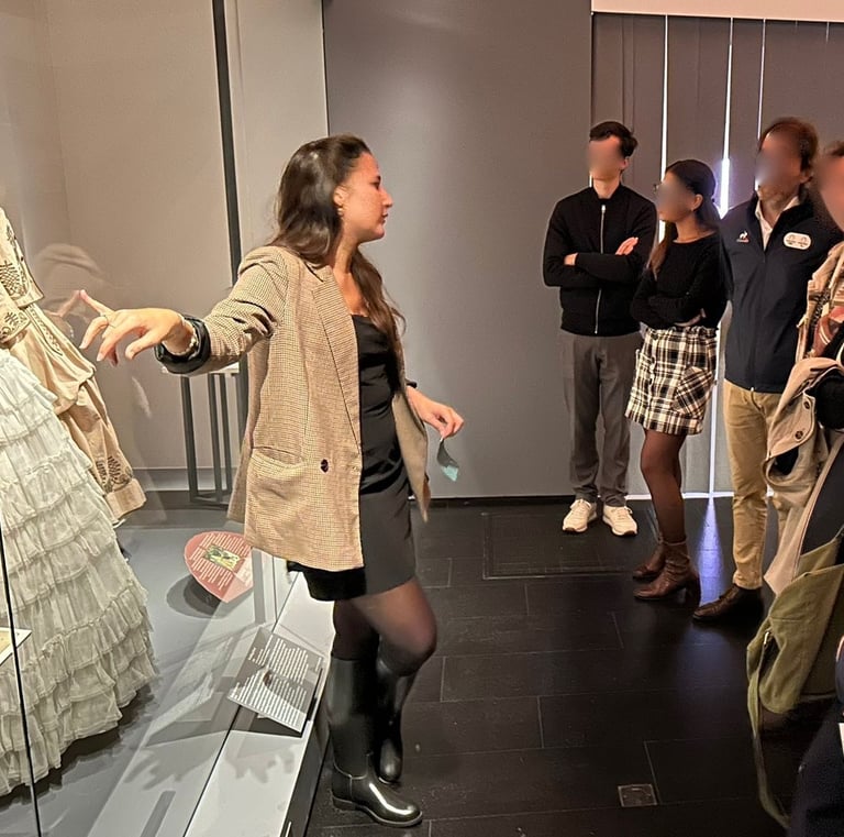 Une guide montre des robes victoriennes à un groupe de visiteurs au musée de la mode de Paris.