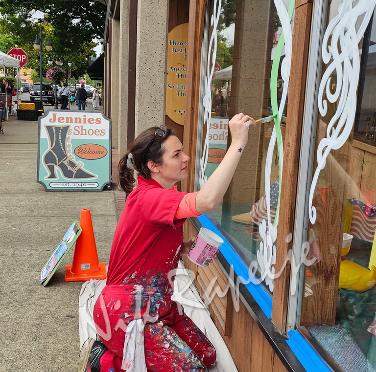 woman painting an artistic design on a shop window