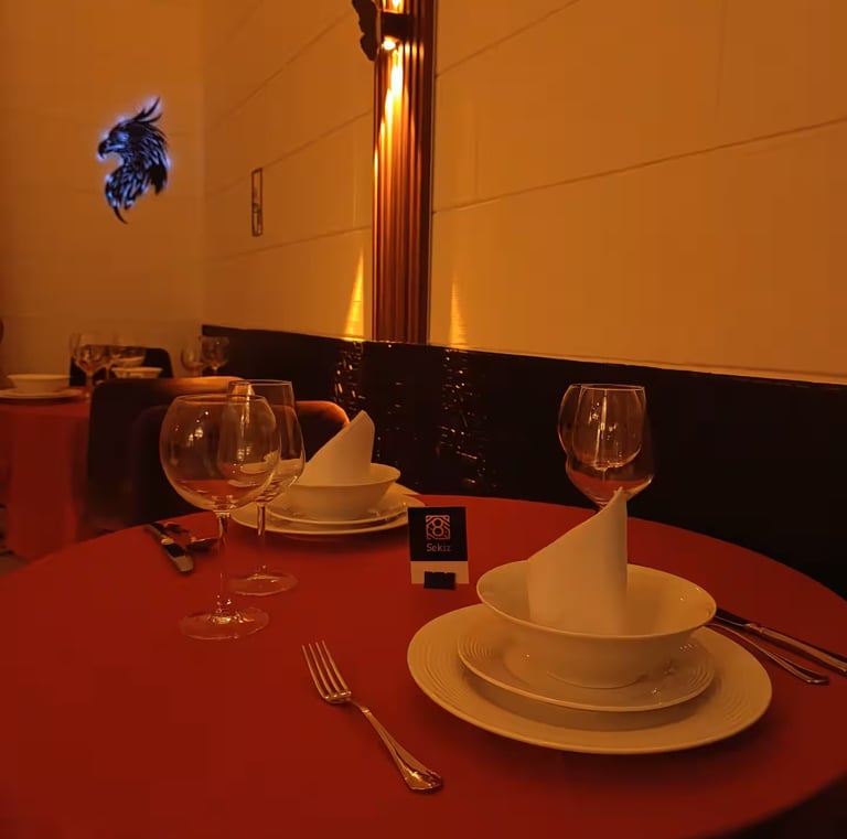 Elegant fine dining table setting with red tablecloth, wine glasses, and white dinnerware.
