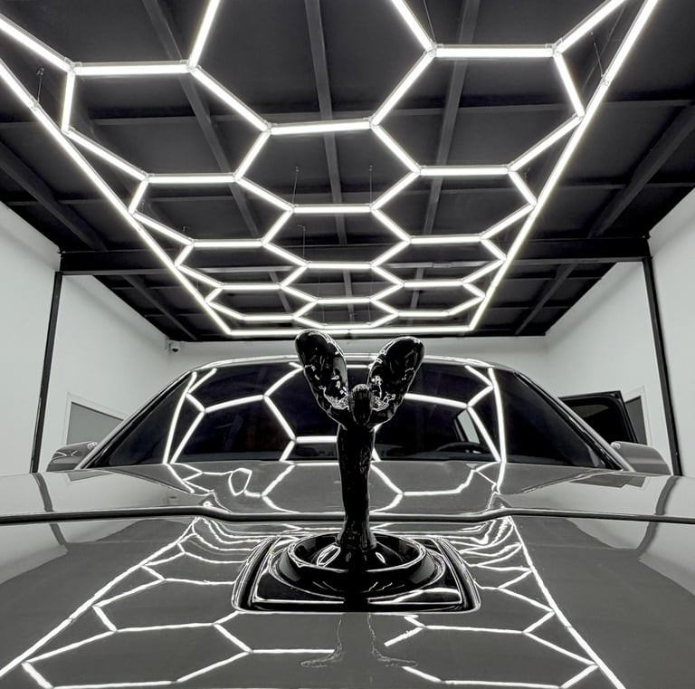 Rolls-Royce Spirit of Ecstasy hood ornament reflecting hexagonal LED garage lights.