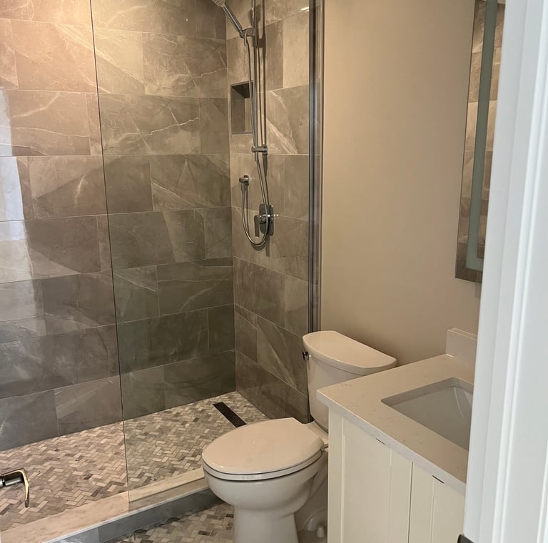 Modern bathroom featuring a glass walk-in shower with gray porcelain tiles and a white vanity.