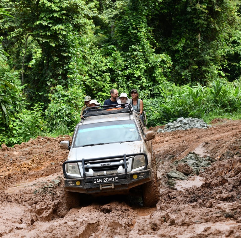 A group of people sitting at the back of the 4x4 truck on their way to the village