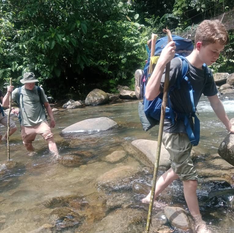 a man with a backpacker walking through a stream