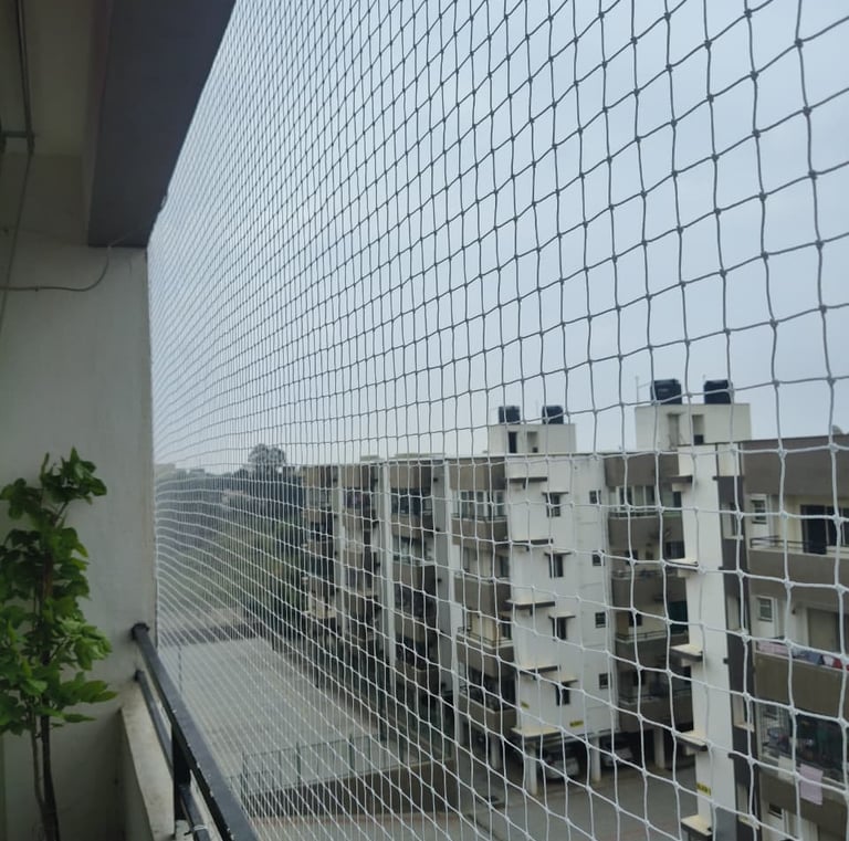 Balcony corner protected by a pigeon net, capturing sunlight filtering through the mesh.