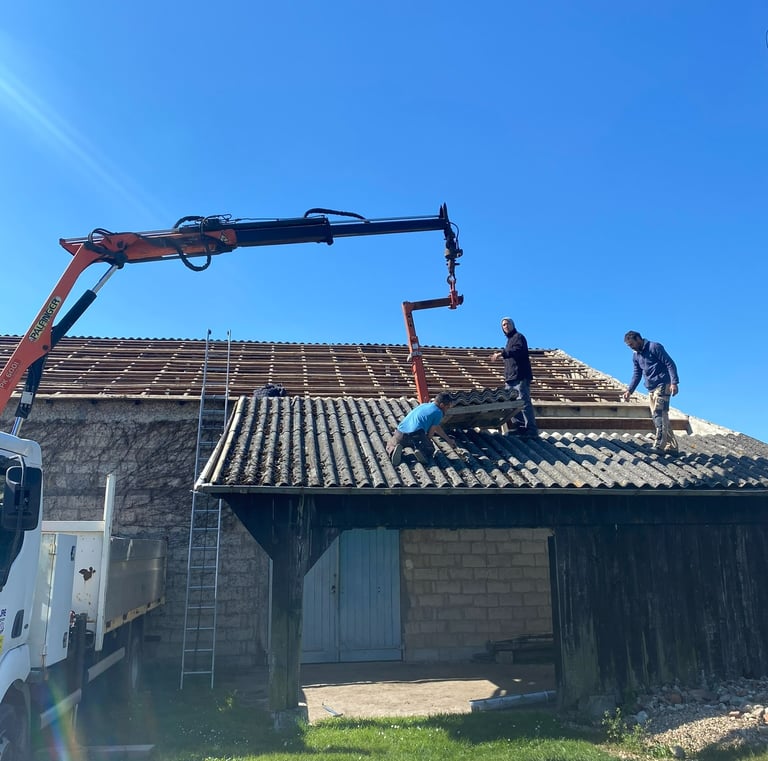 Des couvreurs utilisant une grue camion pour enlever les vieilles tuiles lors d'un projet de rénovat