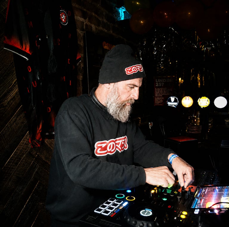 Dacarter DJ wearing headphones mixing music on a controller with a laptop at a club event.
