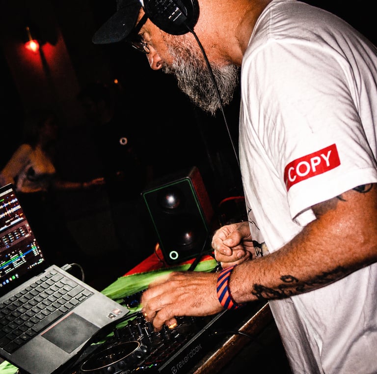Dacarter DJ wearing headphones mixing music on a controller with a laptop at a club event.