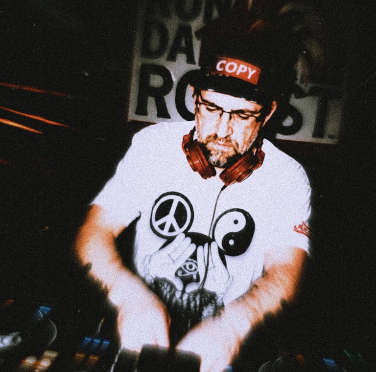 Dacarter DJ wearing headphones mixing music on a controller with a laptop at a club event.