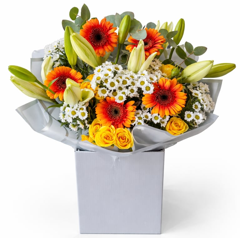 Floral bouquet with orange gerbera daisies, yellow roses, and lilies in a white gift box.