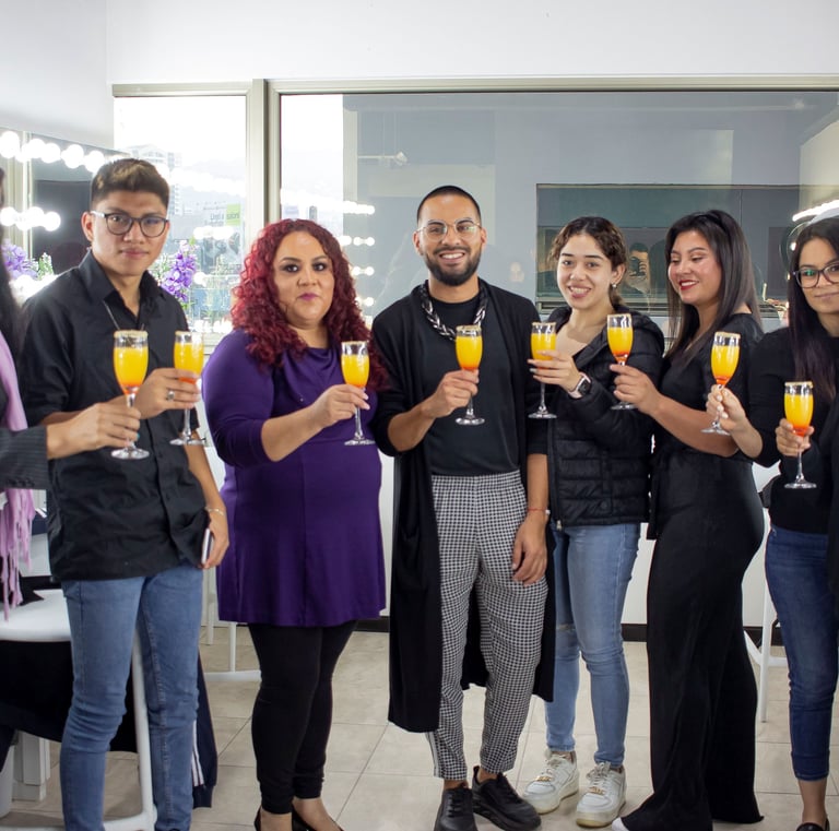 Un grupo diverso de amigos sonriendo y levantando copas de mimosas en un estudio de maquillaje