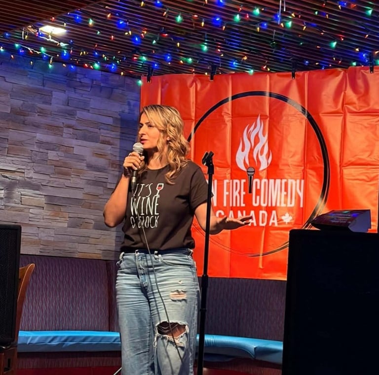 A female stand-up comedian performing live at On Fire Comedy Canada with a microphone and red backdrop.