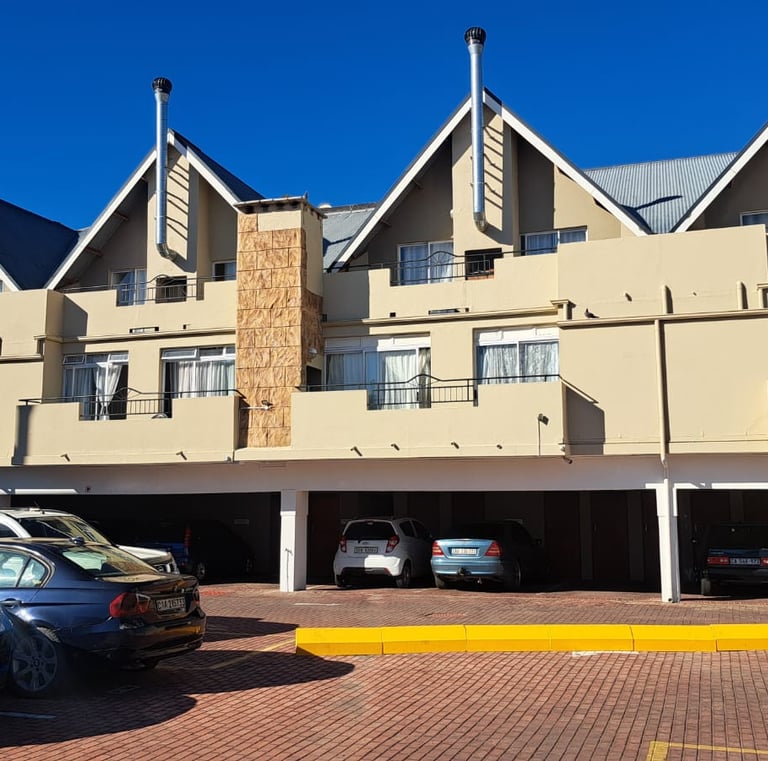 Modern multi-story apartment complex with gabled roofs and a ground-floor parking garage.
