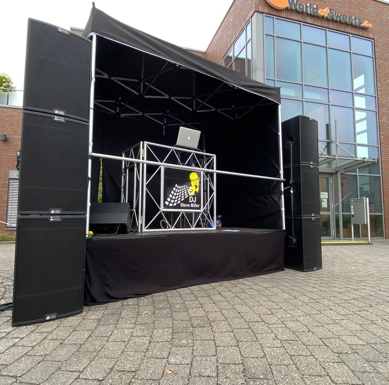 Professionelles Outdoor-DJ-Bühnen-Setup mit großen schwarzen Lautsprechern und Equipment für Events