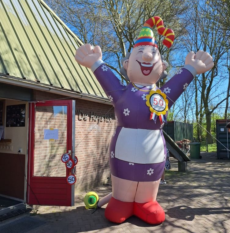 Opblaaspop Sarah, Feestelijke muts op aan de voorkant van een restaurant. Gekleed in Paarse jurk