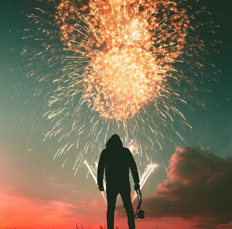 a person standing on a hill with fireworks in the background during sunset