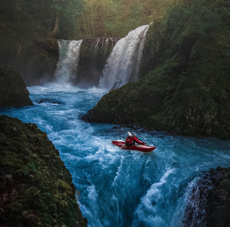 an adventurous man in a red kayak kayaking in the middle of a mountain river waterfall