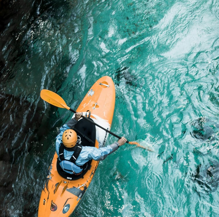 a person in a kayak kayaking in the teal blue water