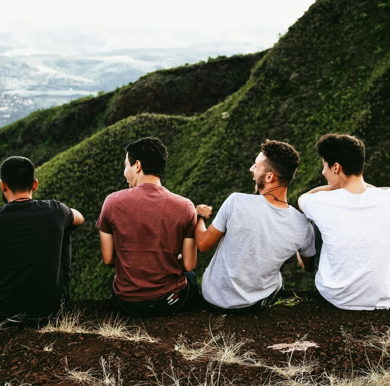 a group of people friends sitting on a hill in the green mountains laughing together