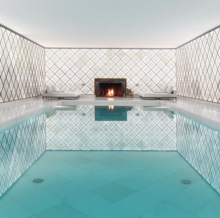 Luxury indoor pool area with white latticed walls and a marble fireplace.