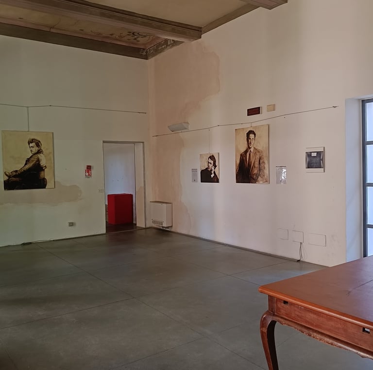 Cesare Pavese portrait paintings hanging on white walls and a vintage wooden desk.