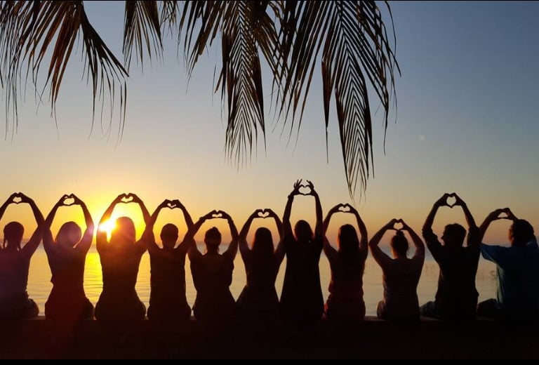 a group of people standing in front of a sunset on their perect gorup vacation