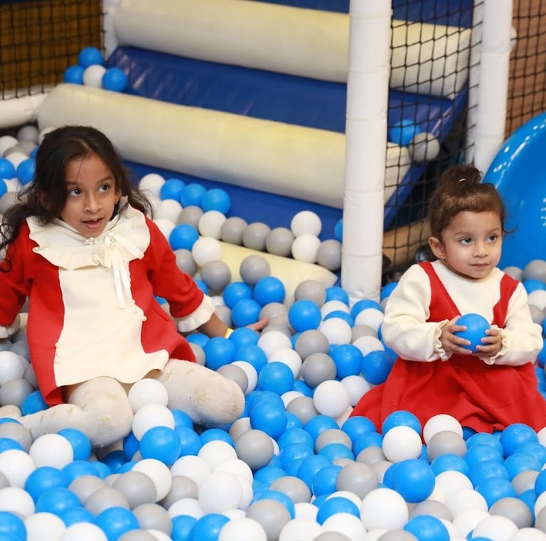 two young girls in red and white dresses playing in a ball pit