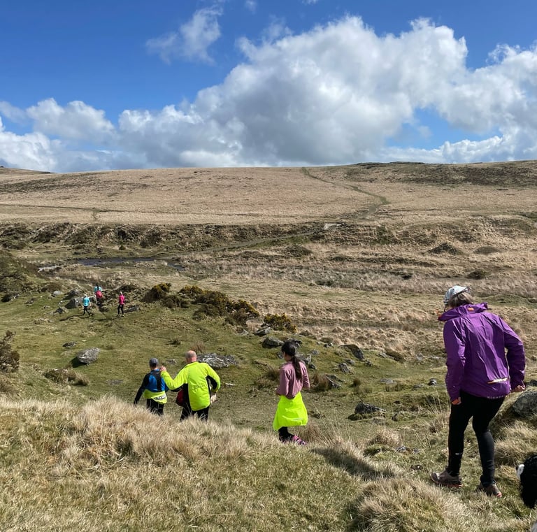 Runners heading down a slope across Dartmoor
