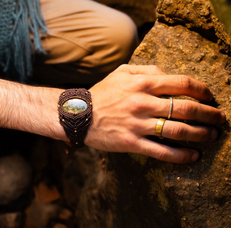 a man's hand wearing woven cuff with semi precious stone and wearing 2 rings