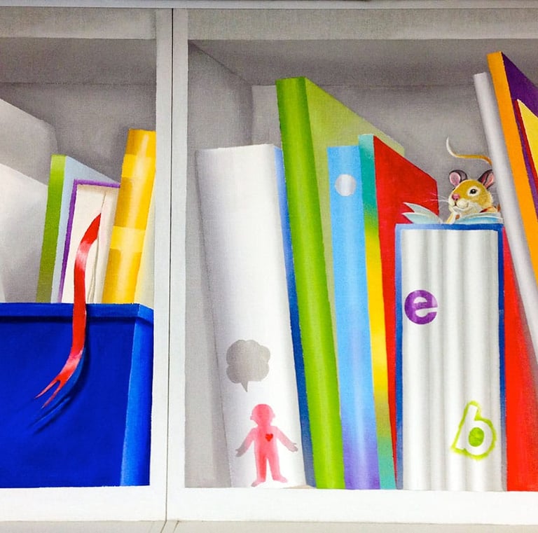 Segment of school library mural depicting brightly coloured hand-painted books, an blue toy box and a little mouse reading.