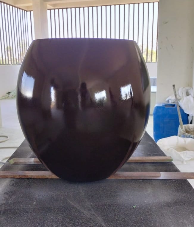 a large brown vase with a large black object in the background