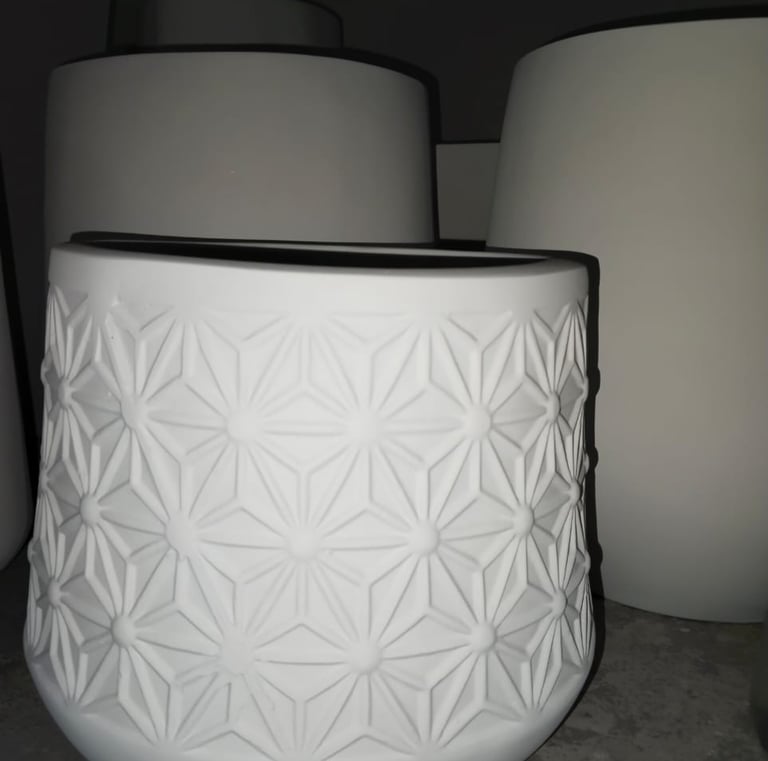 a white vase with a white vase on the ground