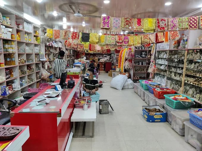 Interior of a Hindu puja store selling spiritual items, deity statues, and colorful religious fabrics.