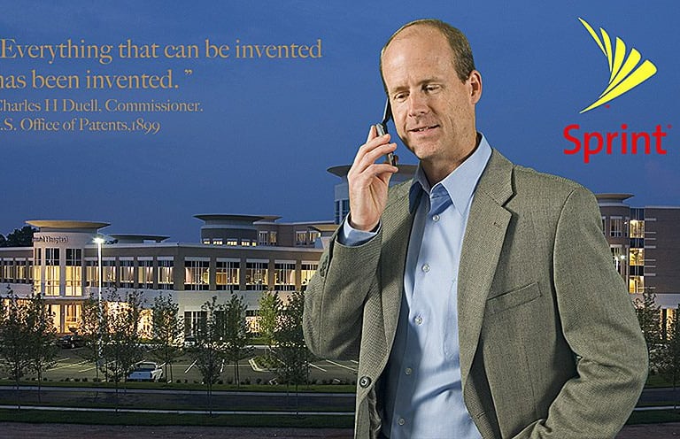 A businessman talks on a mobile phone near a Sprint logo and modern office building.