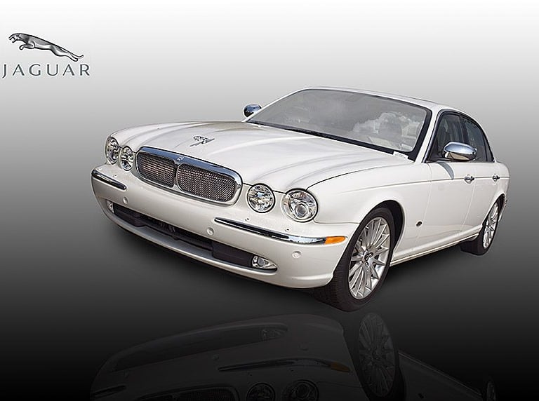 A white Jaguar XJ luxury sedan with chrome trim and signature hood ornament on a gradient background.