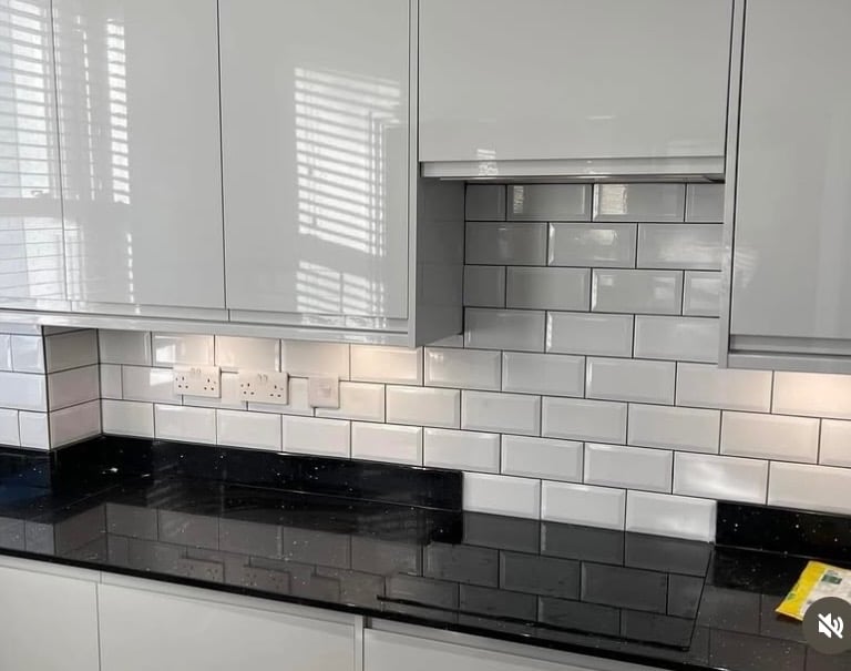 Modern kitchen featuring white gloss cabinets, black quartz countertops, and a white subway tile backsplash.