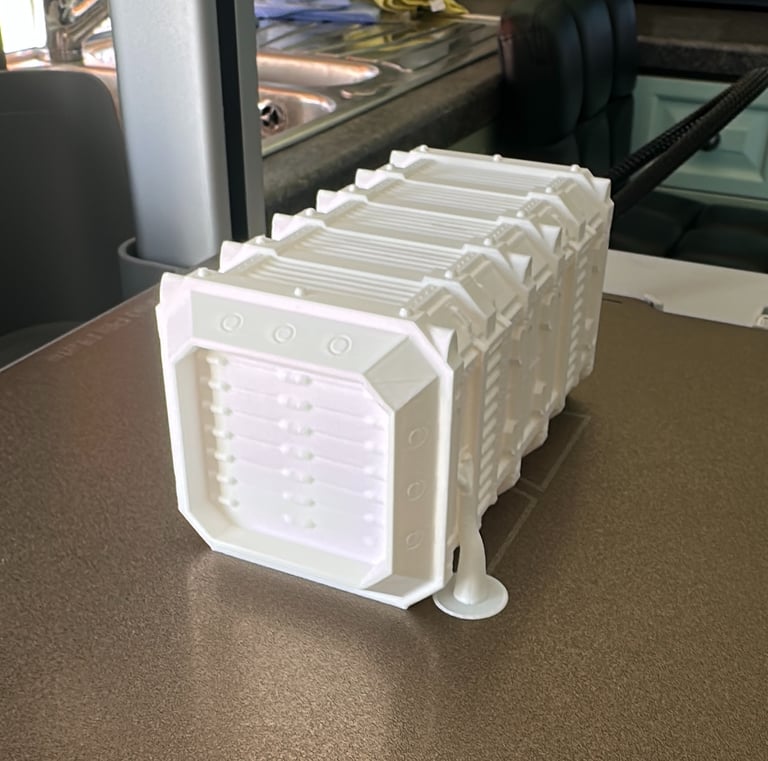 White 3D printed sci-fi shipping container model sitting on a textured printer build plate.