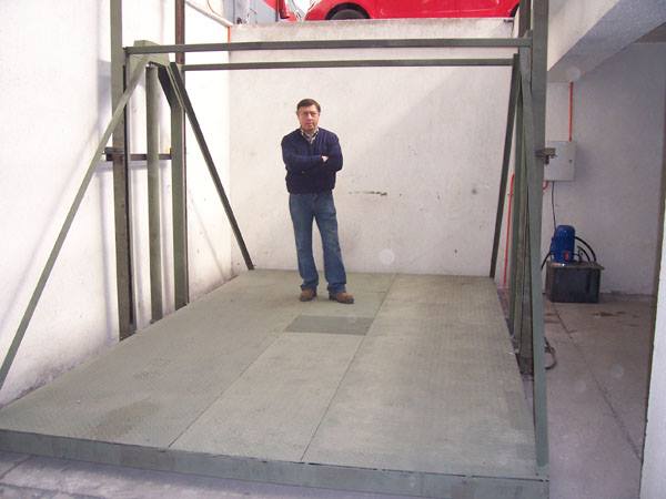 a man standing in a garage with a red car