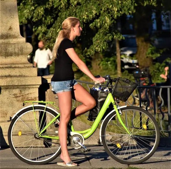 a woman riding a green bicycle with a bicycle basket
