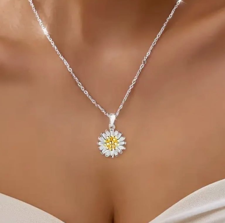 a woman wearing a white dress and a necklace with a yellow flower