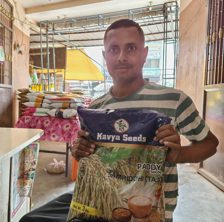 A man holding a bag of Kavya Seeds Paddy Samriddhi high-yield rice seeds in a warehouse.