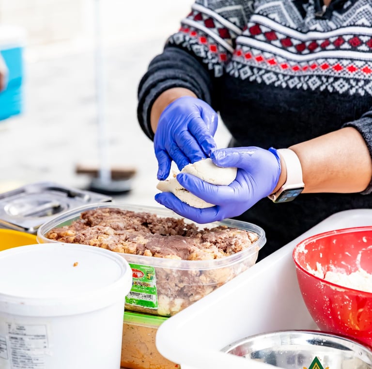 A food vendor wearing blue gloves prepares traditional dough at the Afro Fiesta Festival.