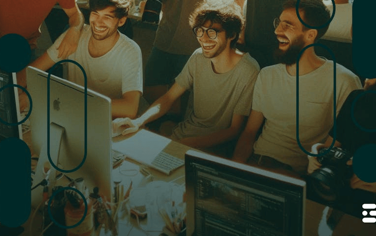 Men laughing at work in front of team computers