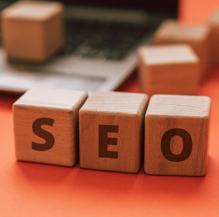 Wooden blocks spelling out SEO in front of blurred out laptop