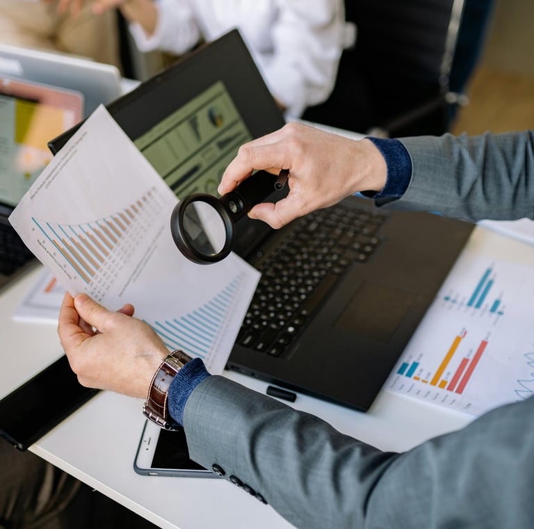 Business man looking at performance reports with a magnifying glass