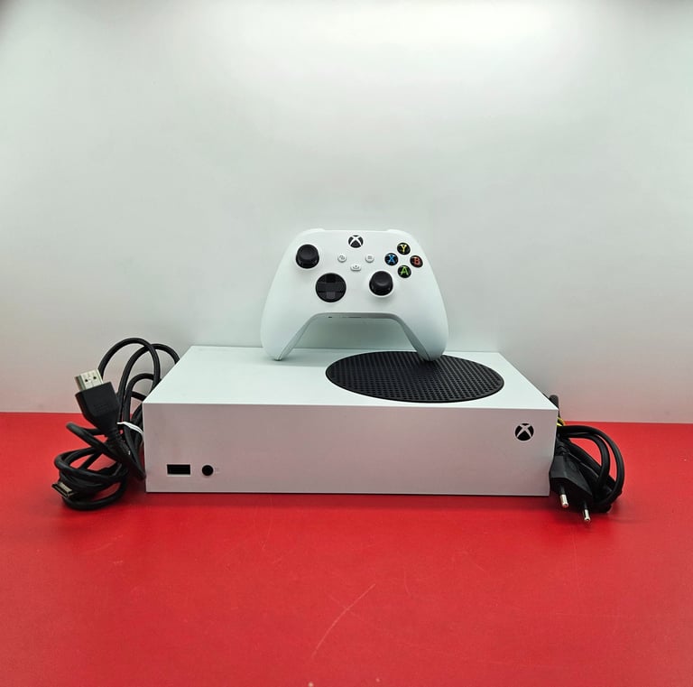 White Xbox Series S gaming console with wireless controller and power cables on a red surface.