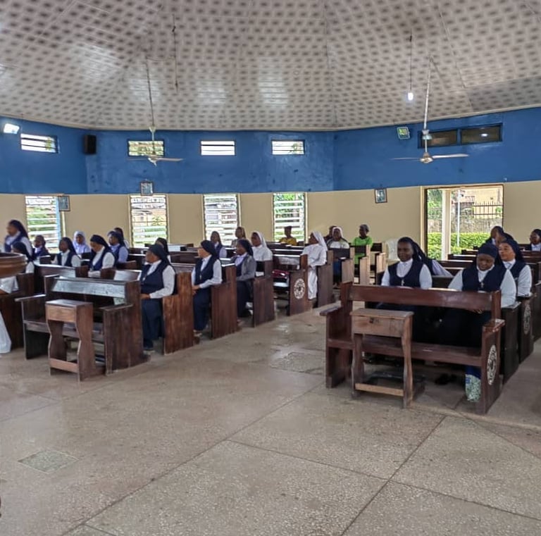 Catholic nuns wearing habits sitting in wooden pews during a church service in a circular chapel.