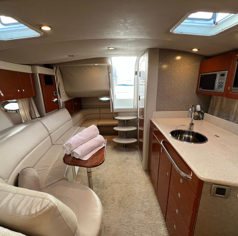 Luxury motor yacht interior featuring a leather sofa, galley kitchen, and wooden cabinetry.
