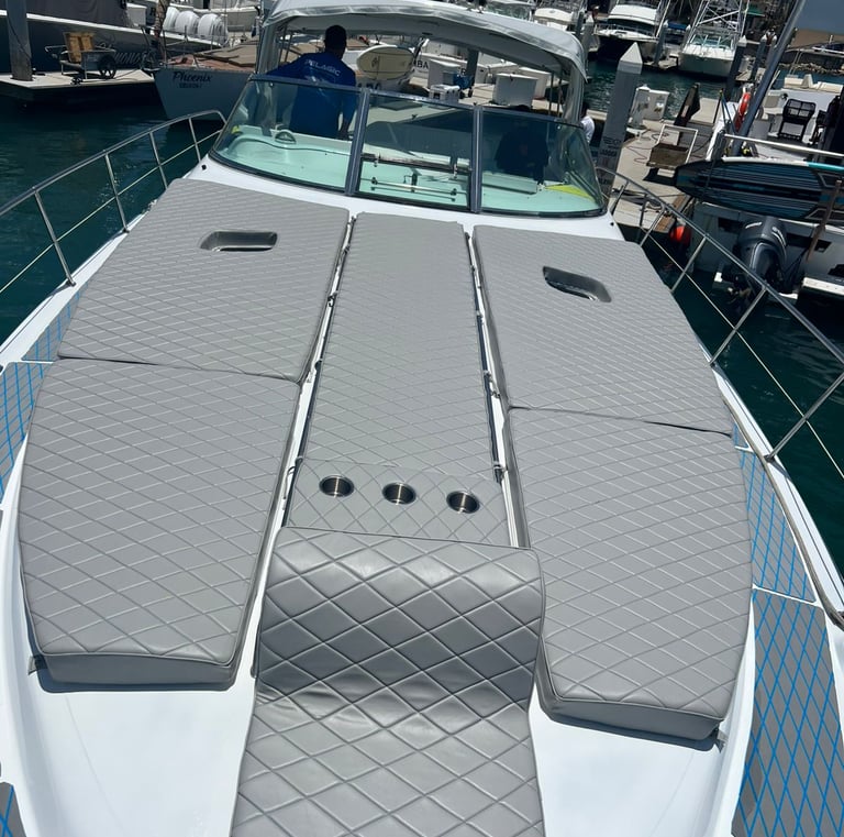 Luxury yacht deck featuring grey quilted sun pads and built-in cup holders docked at a sunny marina.